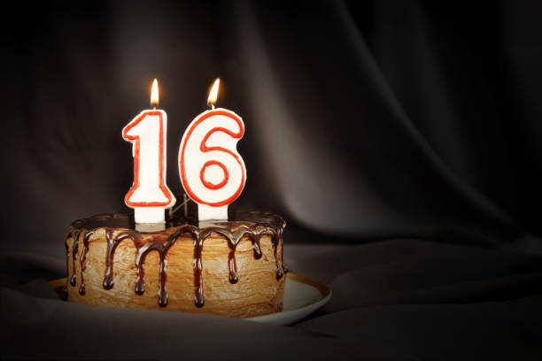 Sixteen years anniversary. Birthday chocolate cake with white burning candles in the form of number Sixteen. Dark background with black cloth Sixteen years anniversary. Birthday chocolate cake with white burning candles in the form of number Sixteen. Dark background with black cloth number 16 stock pictures, royalty-free photos & images