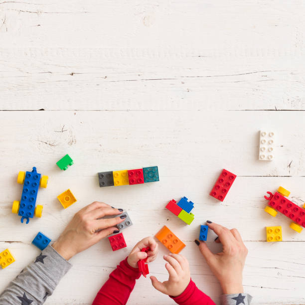 istock Top view on child's and mother's hands playing with colorful plastic bricks. 1137275629