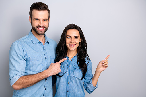 Close up photo amazing she her he him his couple lady guy hold hands arms fingers side empty space indicate direct news wear casual jeans denim shirts outfit clothes isolated light grey background.