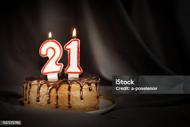 Twenty One Years Anniversary Birthday Chocolate Cake With White Burning Candles In The Form Of Number Twenty One Dark Background With Black Cloth Stock Photo - Download Image Now