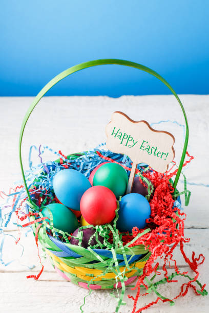 istock Image of basket with colorful eggs on empty blue background on wooden table 1137281882