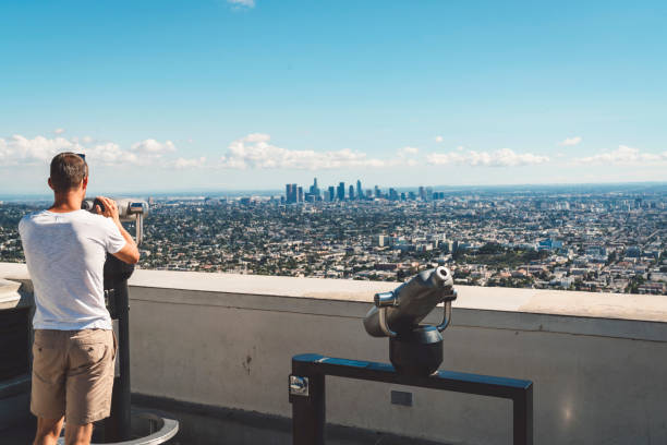 View over LA downtown from Griffith observatory Young men looking on LA down town from Griffith observatory trough the telescope. griffith park observatory stock pictures, royalty-free photos & images
