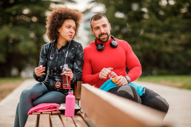 istock Young athletic couple hydrating themselves while taking a break after exercising in a city park 1137283456