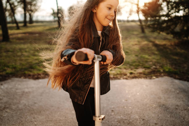 istock Little girl riding scooter in park 1137284037