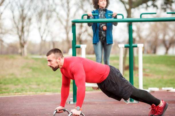 istock Active young people training at a public park, male is doing push-ups while a female is training on the walking machine 1137284271