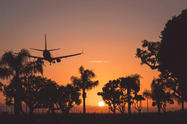 Plane landing, plane take off in Los Angeles airport, LAX at sunset, orange sky. Silhouette of a plane, flying into the sunset.
