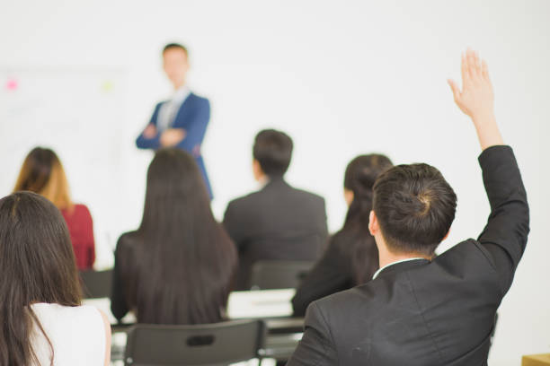 istock Young Asian people audiences seminar group raising up hand for asking the speaker that allow to raising up hand in question and answer time in meeting room see from back side of room. 1137291604