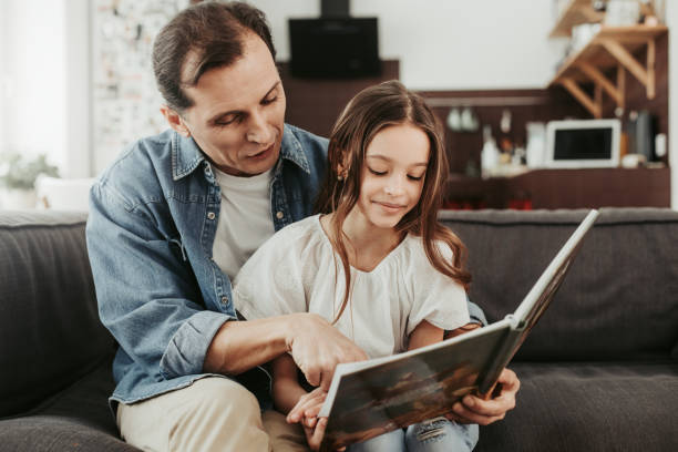 istock Calm man sitting on the sofa and reading book with daughter 1137294059