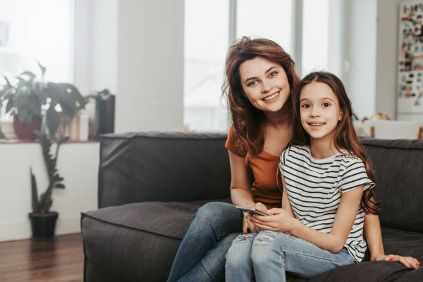 istock Mother and daughter sitting on sofa at home 1137294112