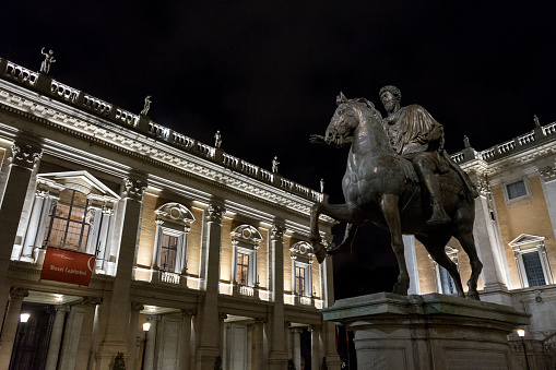 Rome, Italy, 09/03/2019: Capitol square of Rome with copy of the statue of Marcus Aurelius on the right and Capitoline museum on the left, by night.