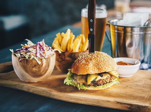 Tasty beef cheeseburger served with french fries, coleslaw salad and beer
