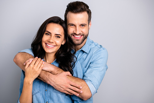 Portrait of cute adorable romantic fellows tender bonding best friends real soulmates enjoying each other placing arms around chest neck in blue denim shirts on grey background.