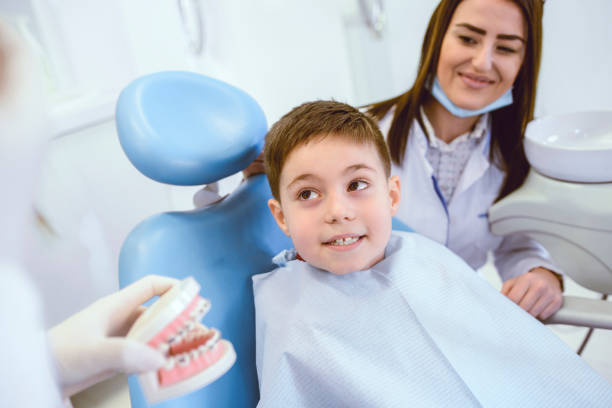 istock Dentists Showing Young Child An Example Of Human Teeth Prosthesis 1137308384
