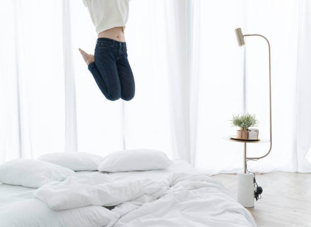 istock woman jumping on bed in bedroom 1137312403
