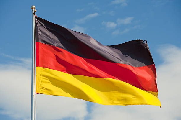Flag of Germany flying on top of flag pole german flag on a pole over beautiful sky german flag photos stock pictures, royalty-free photos & images