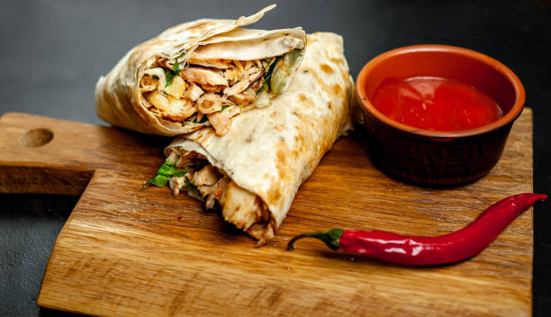 istock Burrito wraps with chicken and vegetables on a cutting board, against a background of concrete, Mexican shawarma 1137314556