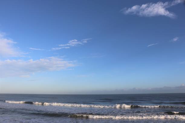 istock Fluffy white clouds in blue sky over coastline and beach with copy space 1137317795