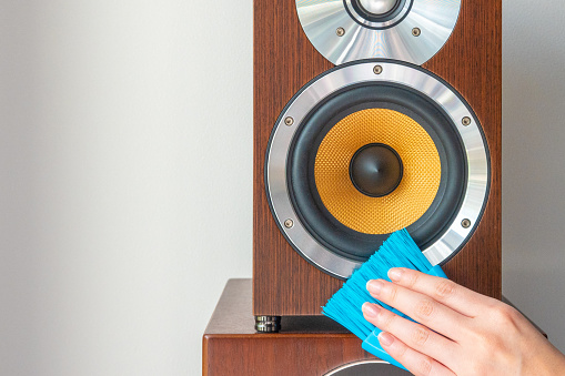 Cleaning a wooden speaker with a brush.