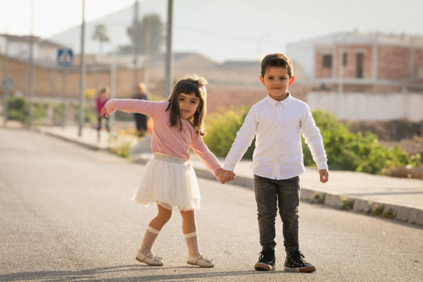 Boy and girl posing holding hands on a road