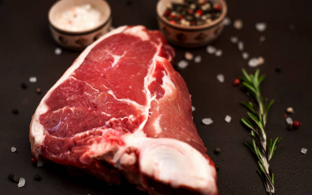 istock Raw meat steak with seasoning on concrete background. Space for text. Beef T-bone steak, top view. Barbecue concept. Ingredients for roasting meat. 1137324927