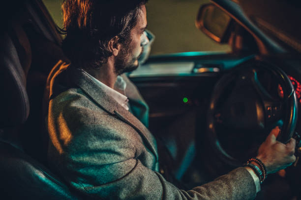 istock Modern guy driving a car in city at night 1137325687