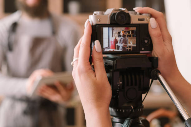 food vlog culinary podcast man camera woman Food vlog. Culinary podcast shooting. Woman with camera recording man wearing apron. Tablet in hands. education training class photos stock pictures, royalty-free photos & images