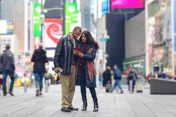 coppia matura in time square - candid women african descent umbrella foto e immagini stock