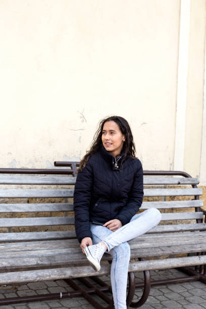 Young woman sitting on bench looking for the train