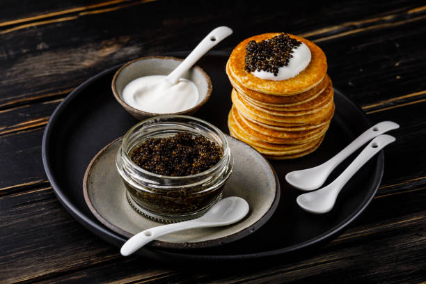 black caviar, mini pancakes y sour cream aperitivo festivo en el fondo oscuro - blini fotografías e imágenes de stock