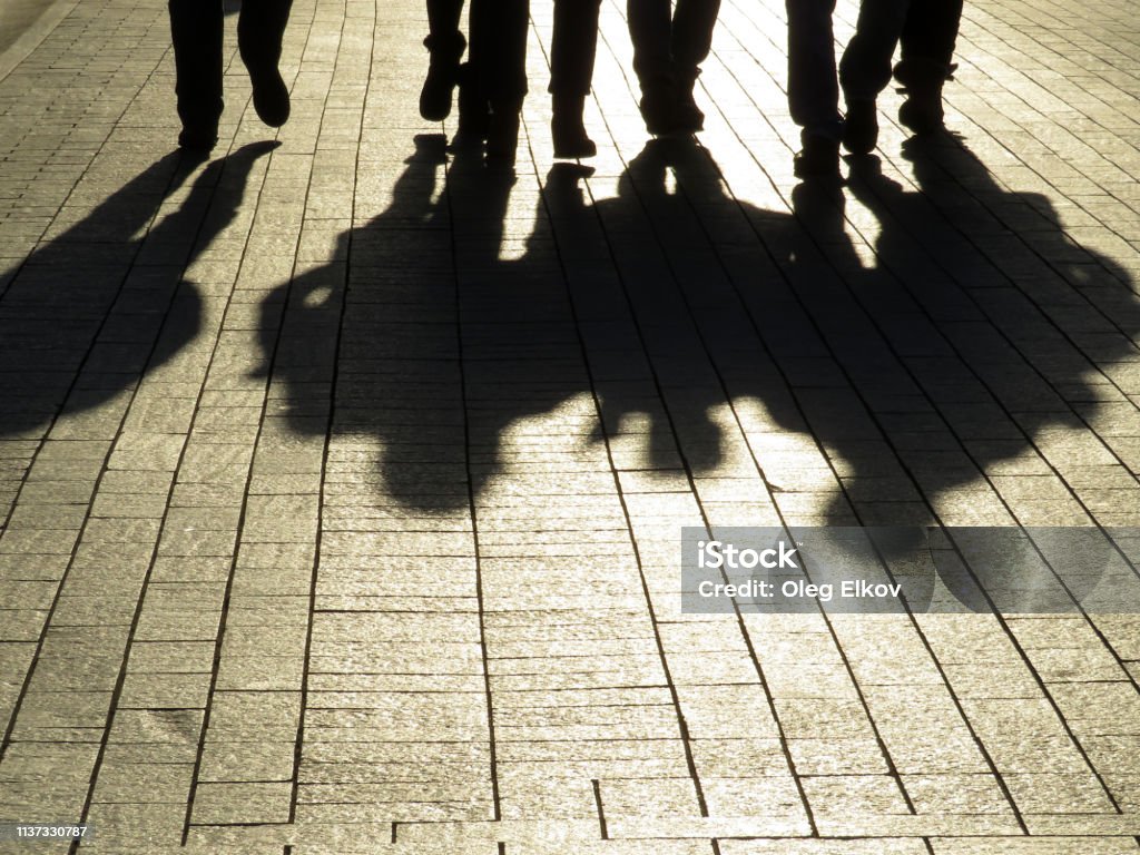 People silhouettes and shadows on the street Crowd walking down on sidewalk, concept of strangers, crime, society, street gang Gang Stock Photo