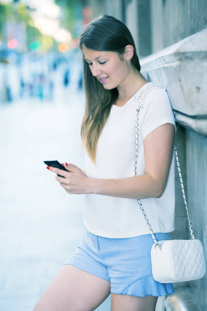 istock Young woman standing with phone near building 1137331484