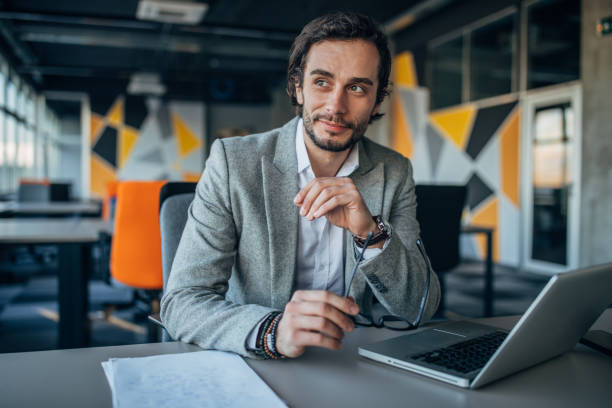 charming businessman sitting in office - charming imagens e fotografias de stock