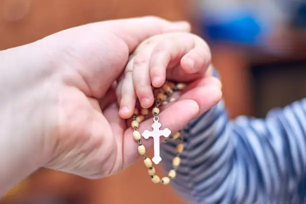 Photo of A child takes a rosary from his dad's hand