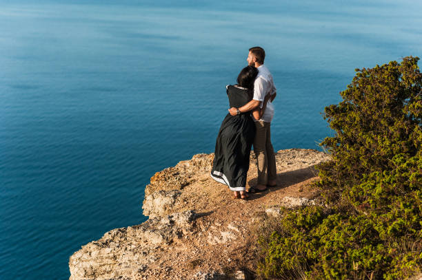 pares no amor no alvorecer pelo mar. honeymoon. viagem de lua de mel. menino e menina no mar. viagem do homem e da mulher. abraços de casal. beijo dos pares. casal recém-casado. amantes. romance do feriado - honeymoon wedding beach couple - fotografias e filmes do acervo