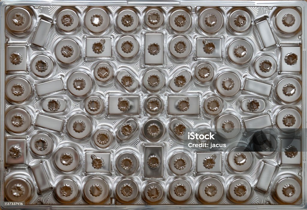 Sweet box. Back of chocolate box gift, shiny silver plastic background with small empty compartments. Abstract Stock Photo