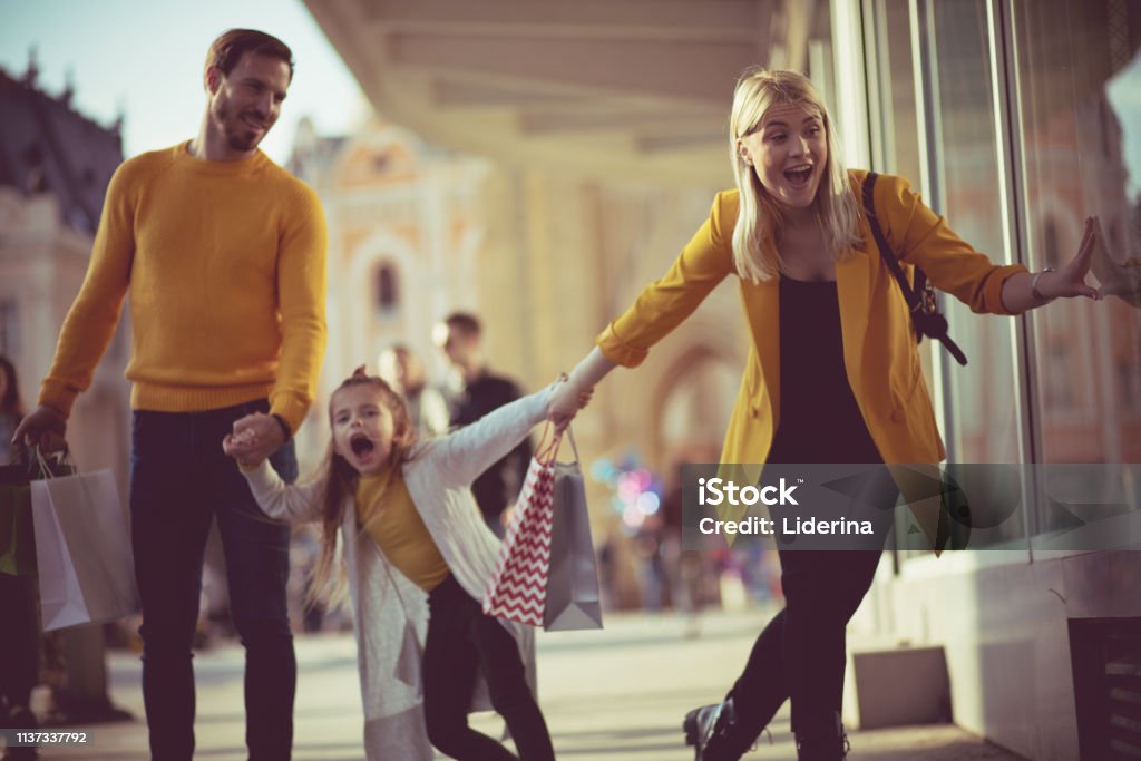 Come on, Mom, you've already bought a lot of things. Come on, Mom, you've already bought a lot of things. Family shopping in the city. Adult Stock Photo