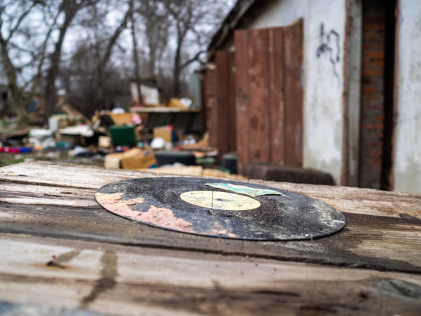 Old musical plate on a dump. A dirty plate among garbage. The thrown-out phonograph record