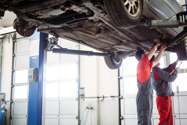 istock Two mechanics in uniform are working in auto service with lifted vehicle 1137339691