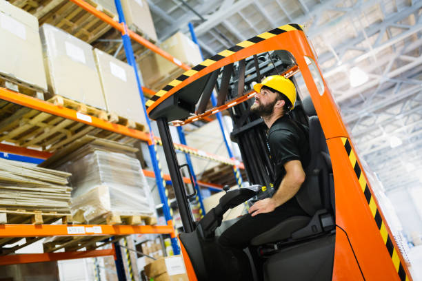 Warehouse worker doing logistics work with forklift loader Warehouse industry worker doing logistics work with forklift loader stacker stock pictures, royalty-free photos & images