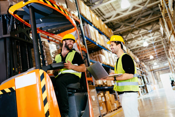 Warehouse workers working together with forklift loader Warehouse workers working together with forklift loader trasnporter stacker stock pictures, royalty-free photos & images