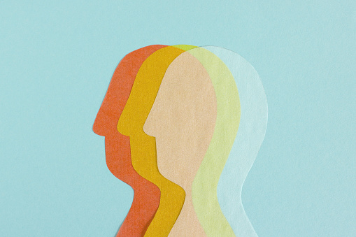 Composed row of transparent paper cutout of heads overlapped on blue background