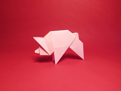 Origami pink pig on a red background