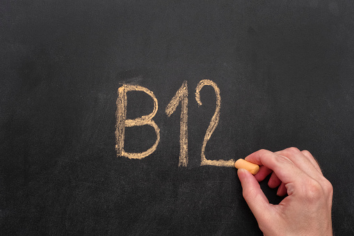 Man writing word B12 on chalkboard. Vitamin B12 Concept. Close up.