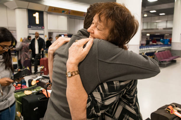 Emotional Reunion in Airport A close-up side-view shot of a man and women hugging eachother at an airport, the woman can be seen smiling with happiness as her friend returns home. airport hug stock pictures, royalty-free photos & images