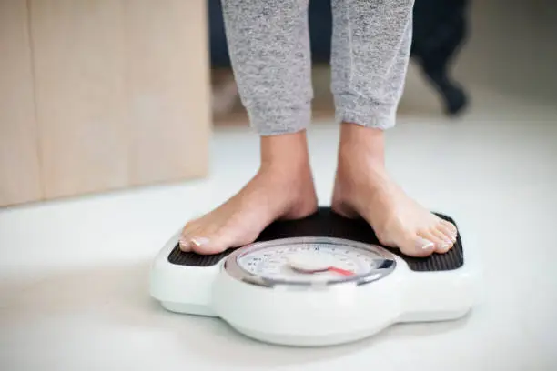 Close Up Of Woman Standing On Bathroom Scales At Home