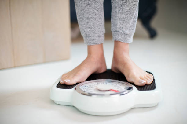 close up of woman standing on bathroom scales at home - weight scale dieting weight loss imagens e fotografias de stock