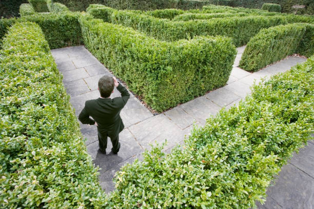 Top view of a caucasian businessman lost in a maze Top view of a caucasian businessman lost in a maze themes of lost the way forward decisions maze road street confusion stock pictures, royalty-free photos & images
