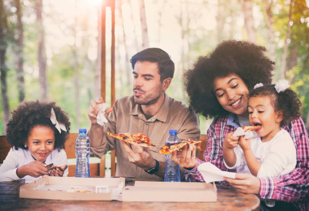 family eating pizza outdoor together - pizza eating african descent lunch imagens e fotografias de stock