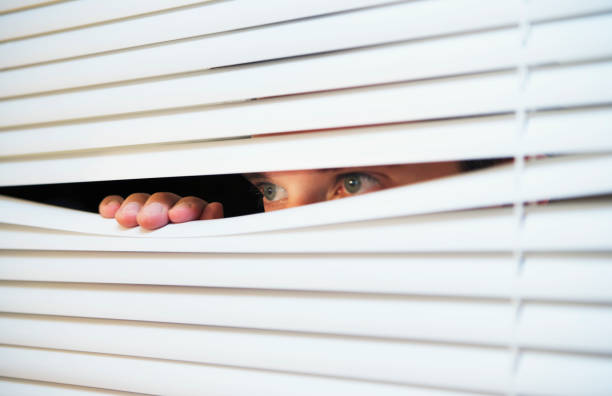 istock Caucasian man looking through the slats of a blind 1137354280
