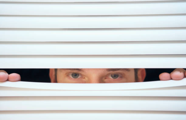 istock Caucasian man looking through the slats of a blind 1137354426